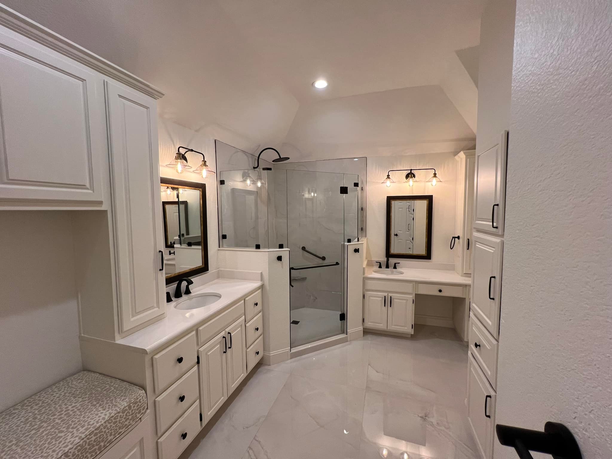 Large white master bathroom with dual vanities and corner glass shower