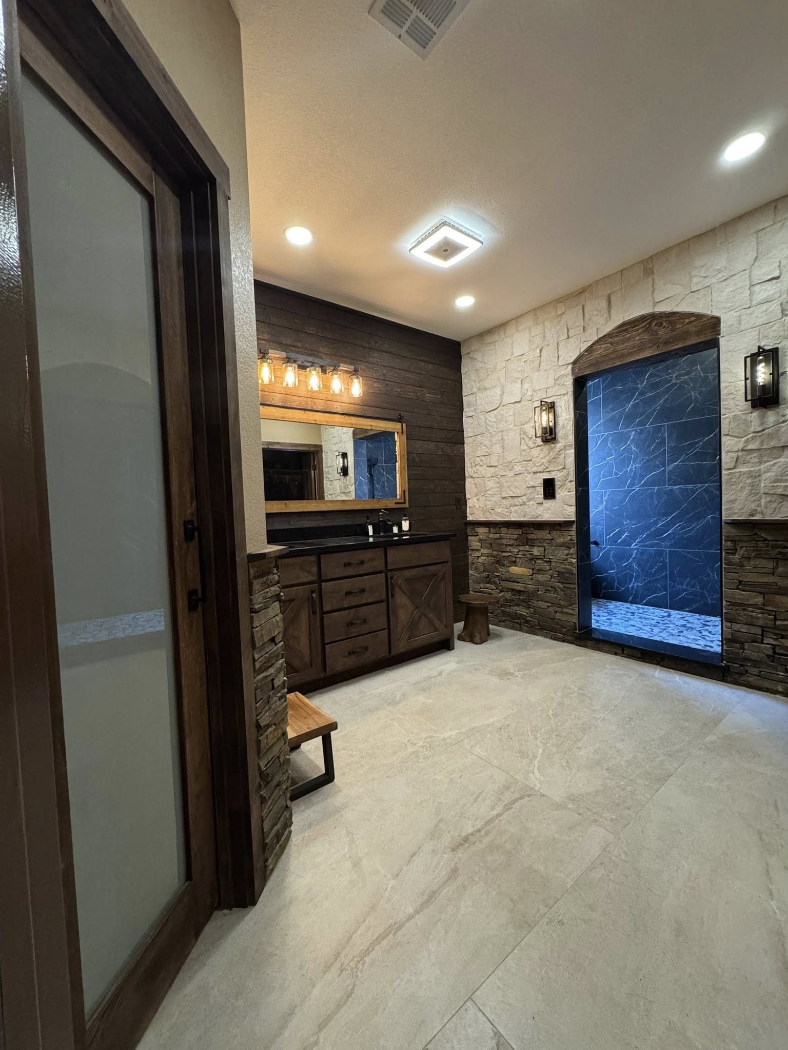 Custom bathroom with stacked stone walls and arched shower entry