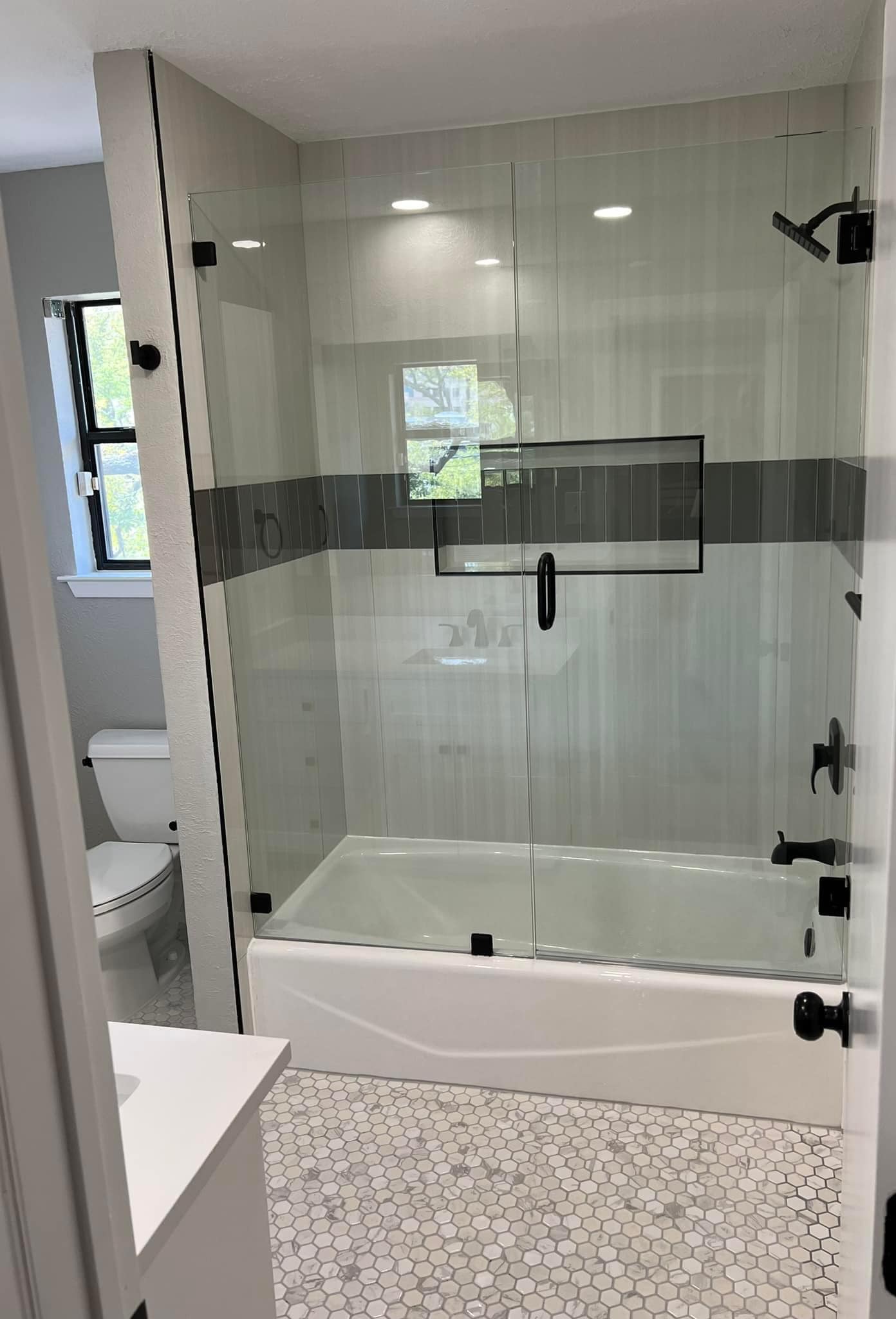 Tub and shower combo with frameless glass door and hex tile floor