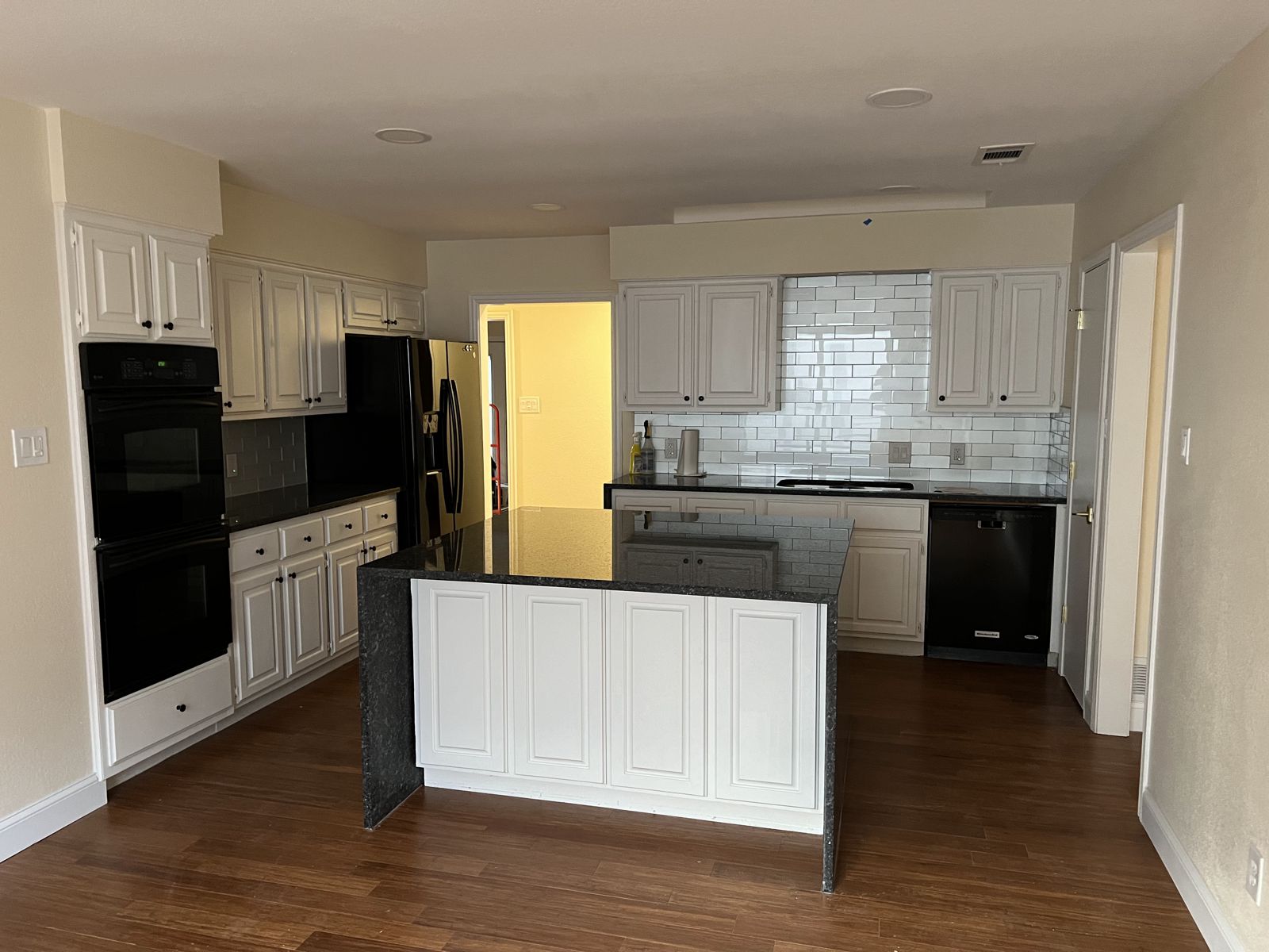 Kitchen remodel with white cabinets, black granite island and hardwood floors