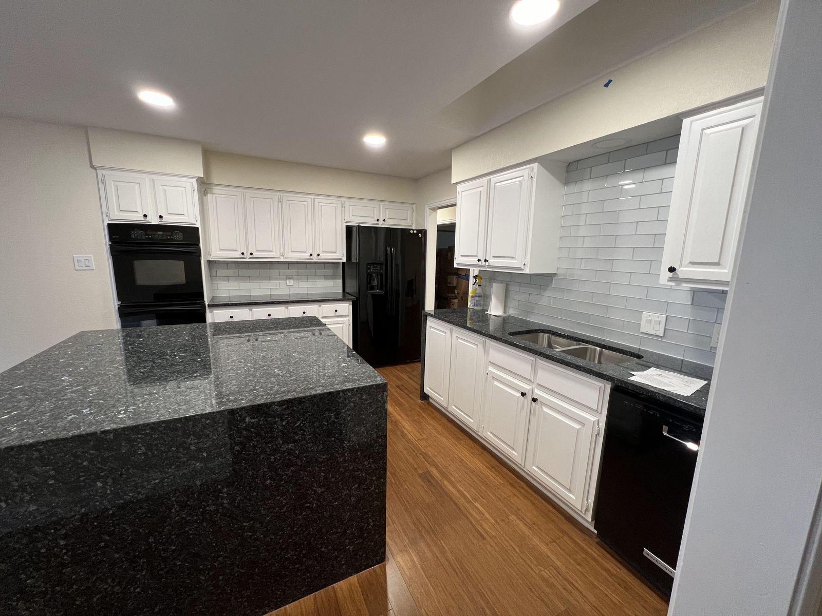 Black granite waterfall island with white cabinetry