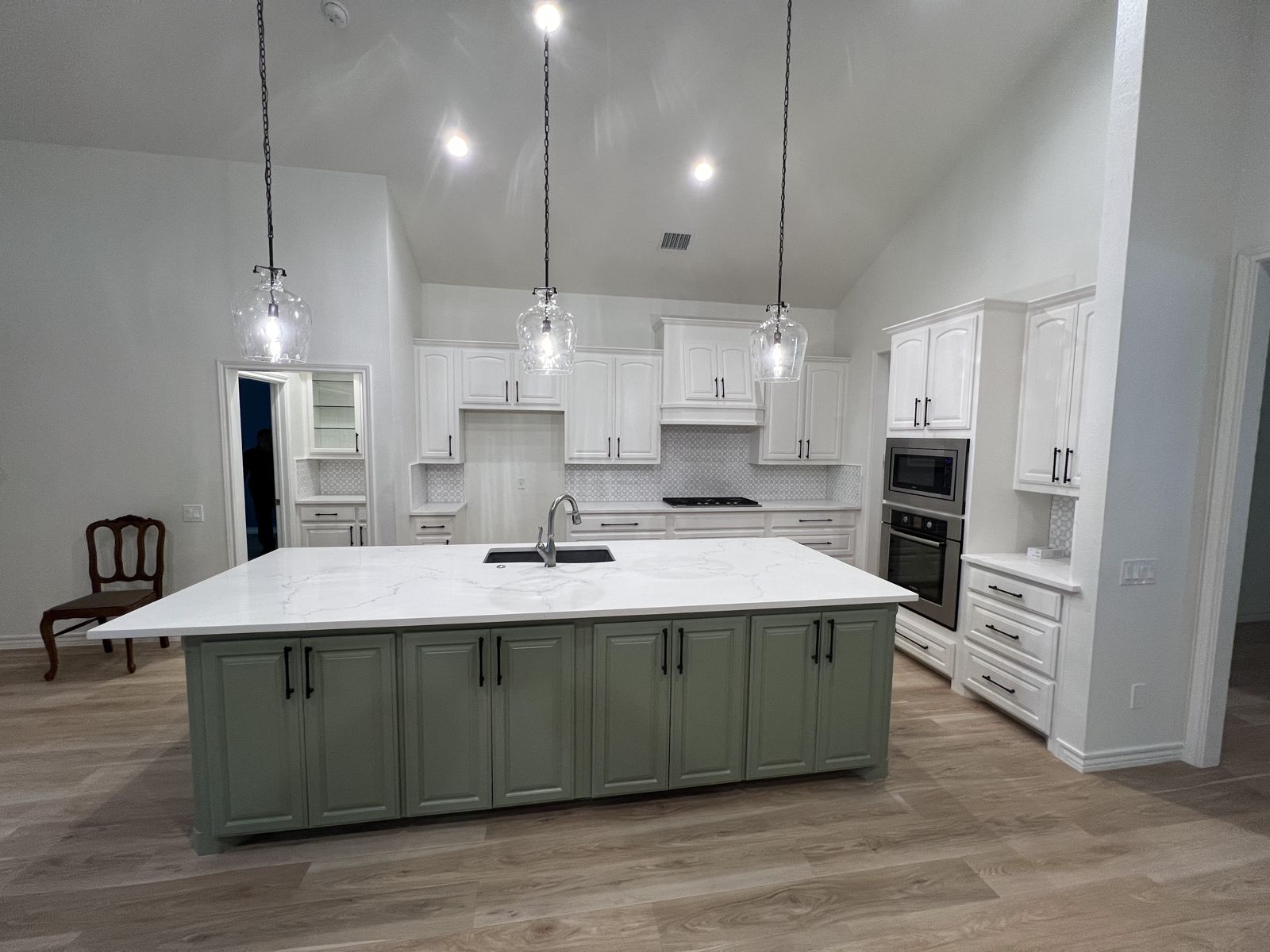 Open kitchen remodel with large island, white cabinetry and luxury vinyl plank flooring