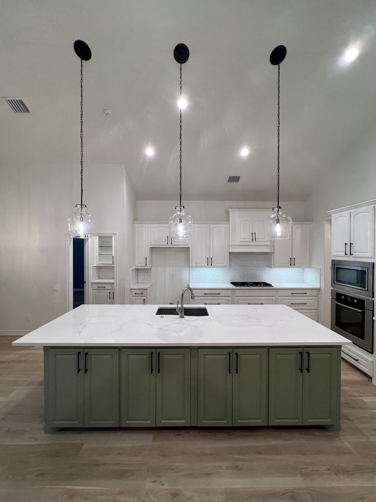 Kitchen remodel with sage green island, quartz countertops and pendant lighting in Fort Worth