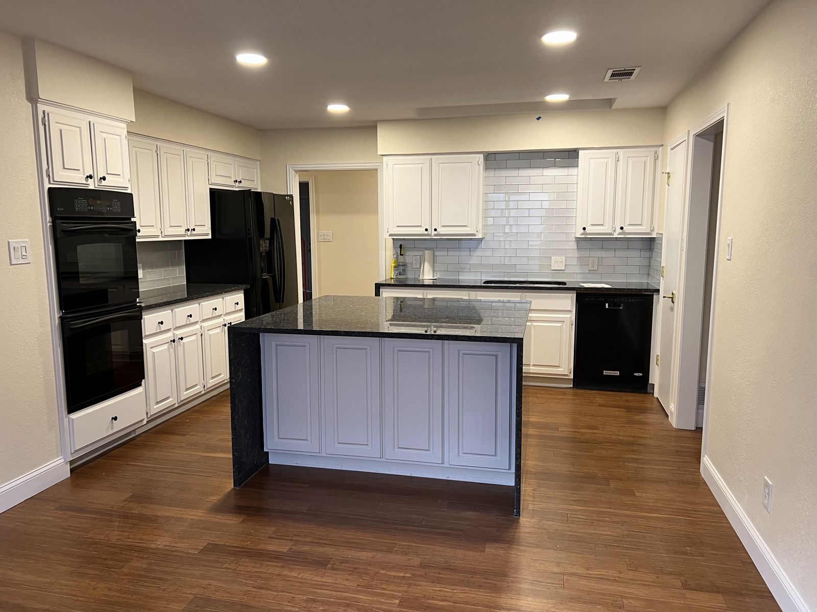 Remodeled kitchen with white shaker cabinets, subway tile backsplash and black appliances