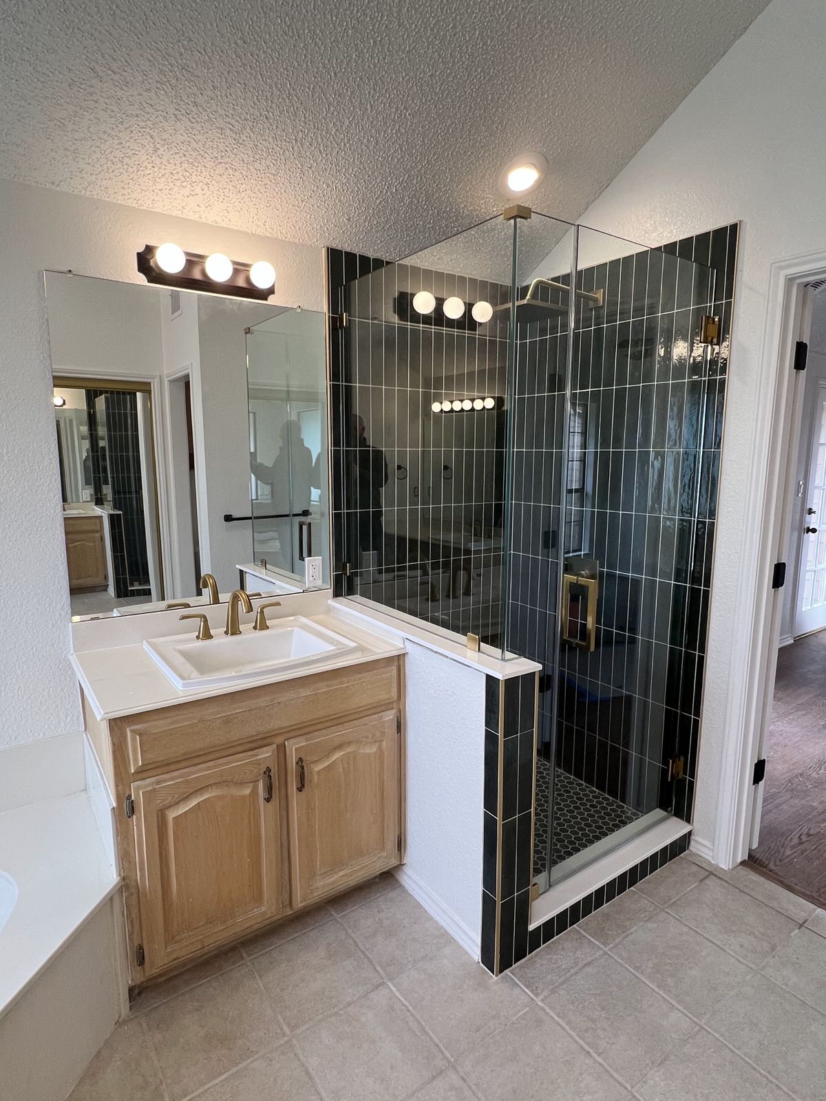 Walk-in shower with dark green vertical tile and frameless glass