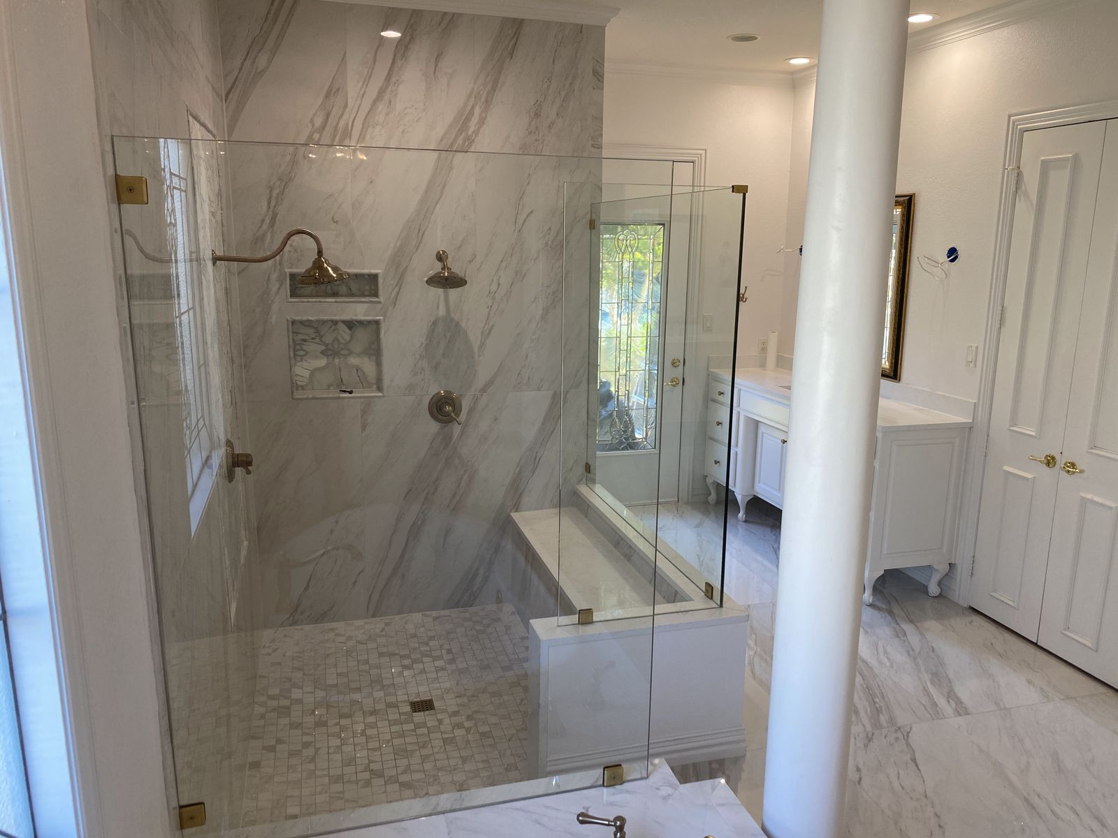 Large frameless glass shower with marble-look porcelain tile