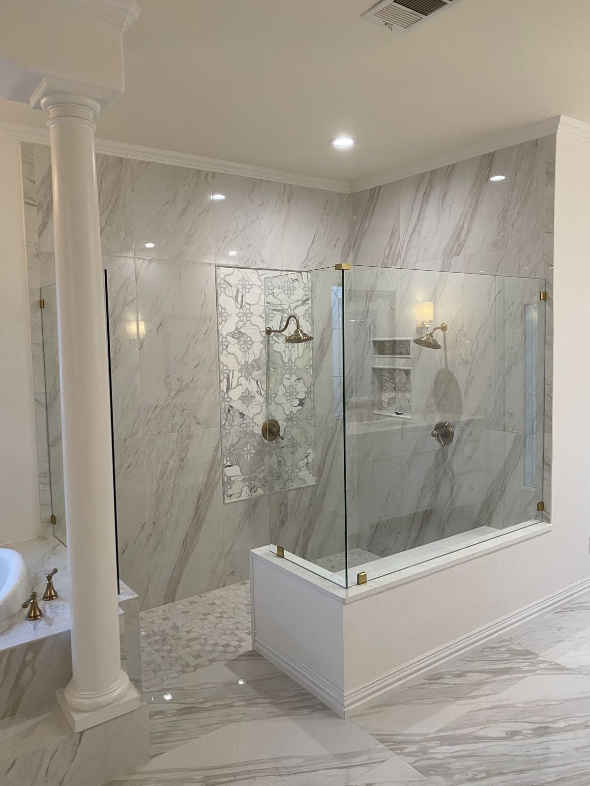 Marble-look walk-in shower with frameless glass and built-in bench