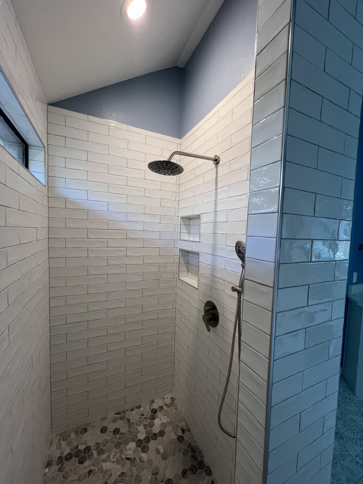 Subway tile shower with pebble floor and matte black fixtures