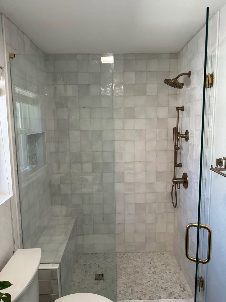 Zellige-style tile shower with brass fixtures and frameless glass