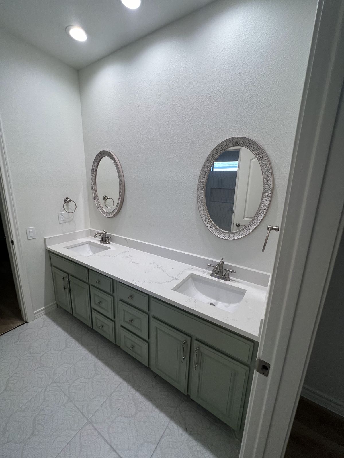Double vanity with sage green cabinetry and round mirrors